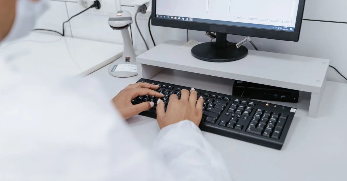 Scientifique en blouse blanche utilisant un ordinateur dans un laboratoire, se concentrant sur l'analyse des données.