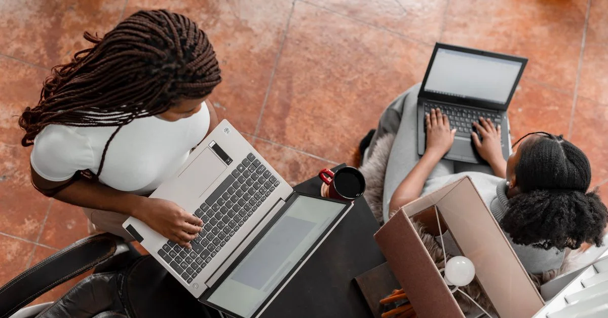 Deux femmes utilisant des ordinateurs portables dans un espace de travail lumineux, axées sur la collaboration et la productivité.