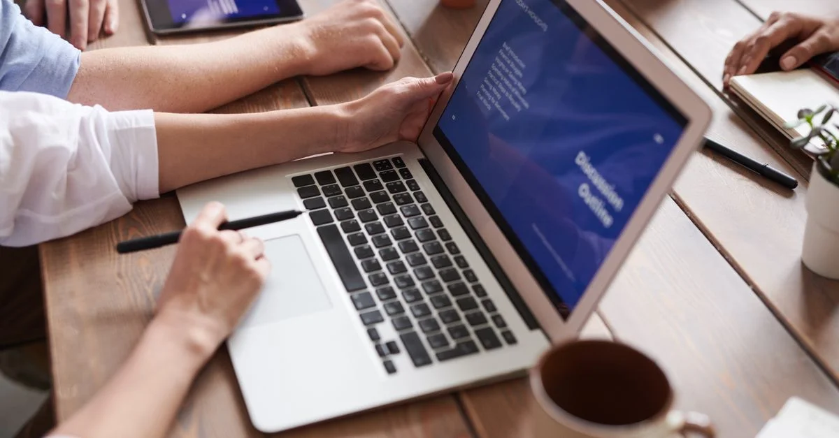 Des membres de l'équipe brainstorment avec des ordinateurs portables et du café dans un espace de bureau moderne, favorisant la collaboration.