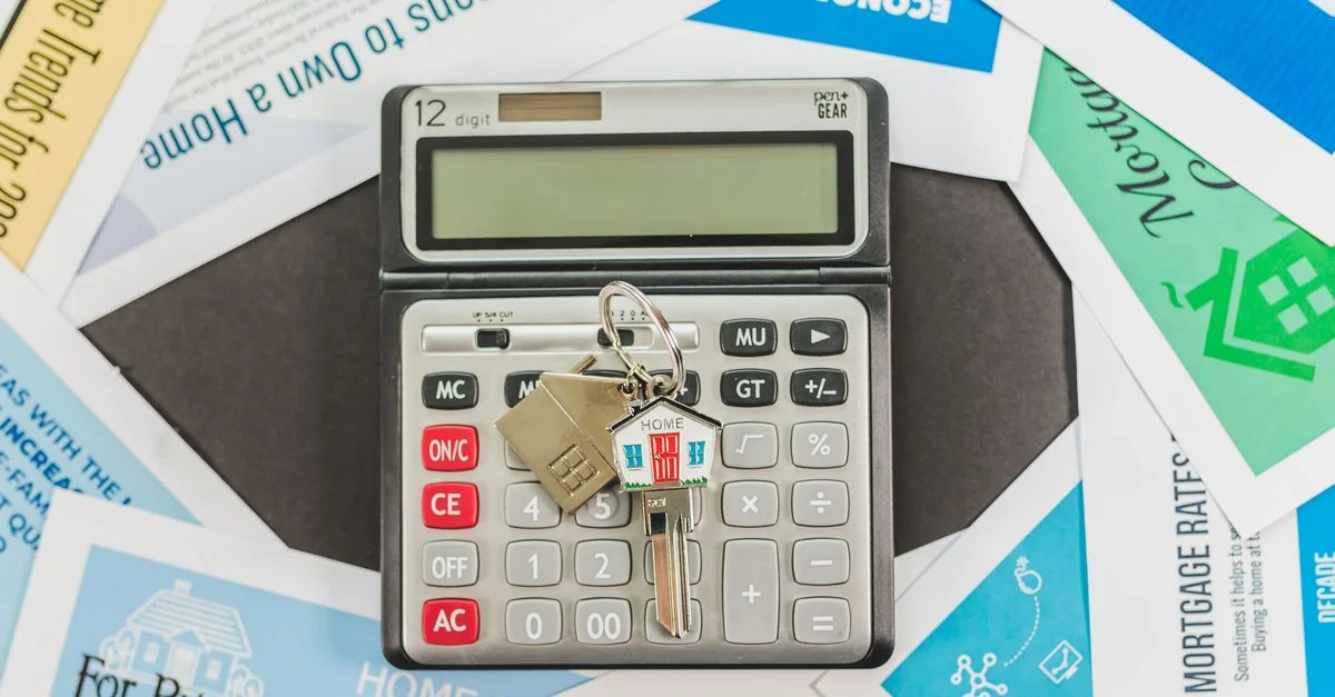 Une calculatrice avec des touches et des documents immobiliers symbolise les finances liées à l'achat d'une maison.