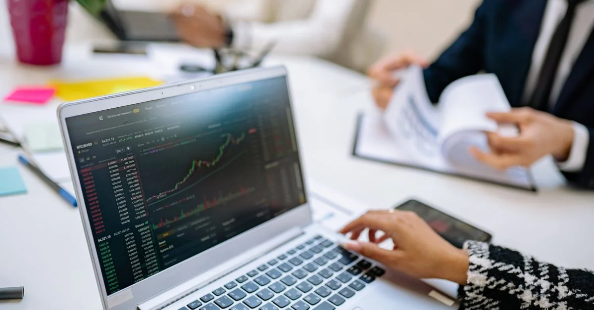 Une équipe d'affaires analyse les tendances du marché des cryptomonnaies en utilisant un ordinateur portable avec des graphiques et des données.